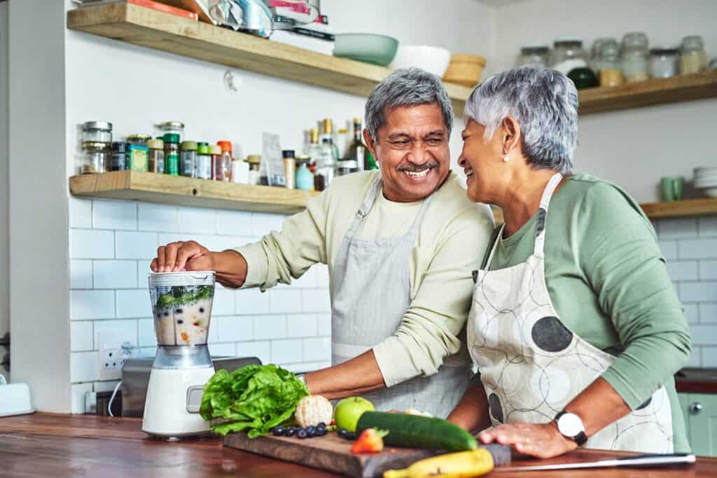 Man and woman making a healthy smoothie after learning the benefits of healthy eating to prevent plaque buildup in arteries