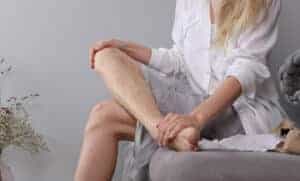woman looking at spider veins on her lower leg
