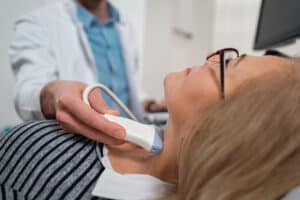 Endocrinologist doing ultrasound of thyroid gland on a senior female patient