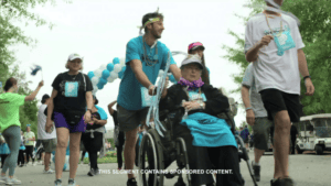 Man pushing woman in wheelchair in a parade
