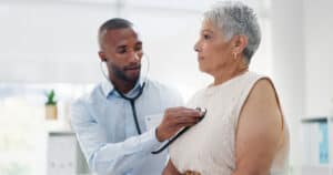 Stethoscope, examination and doctor with senior woman at hospital for lungs, chest or breathing assessment. Heart, listen and elderly patient consulting cardiologist for heartbeat, pulse or checkup