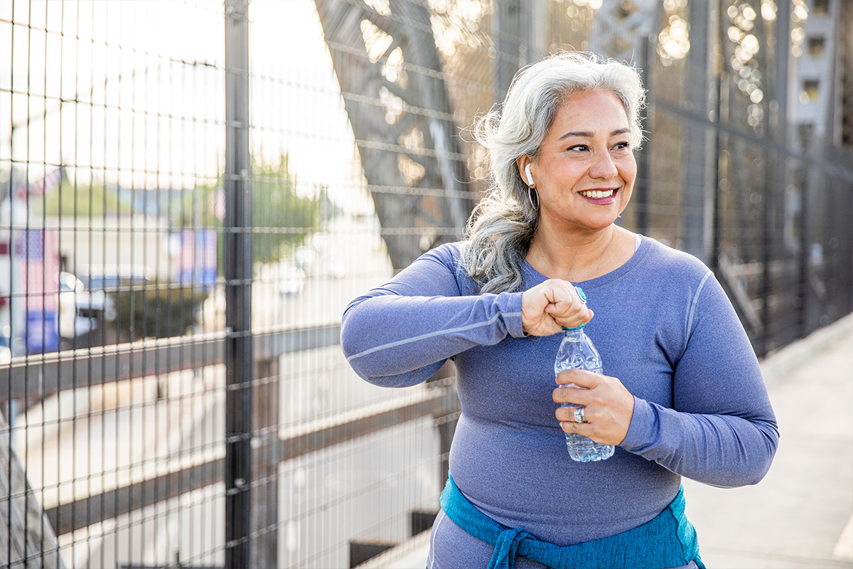 Woman on bridge opening a water bottle