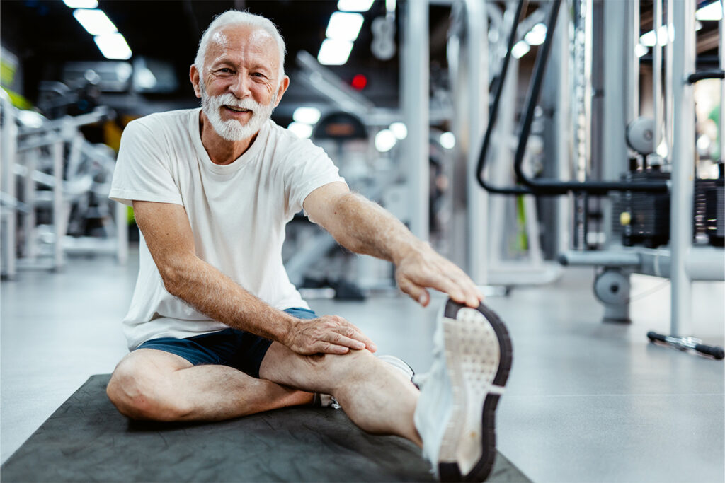 Older man in gym doing stretches