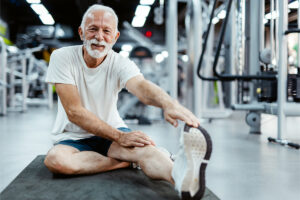 Older man in gym doing stretches