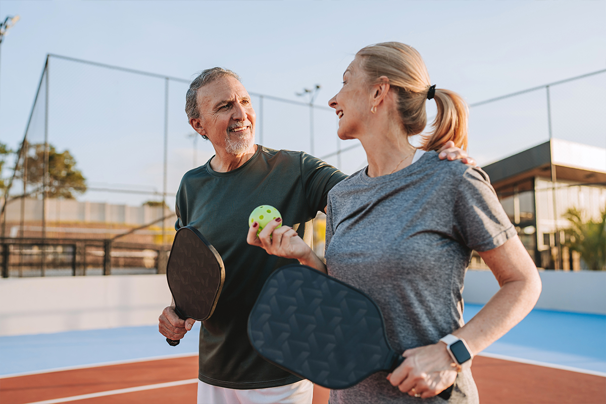 Older couple standing on a tennis court