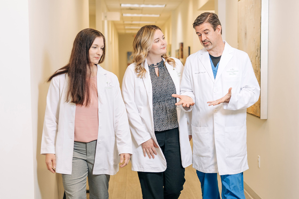 Three medical professionals walking down a hallway.
