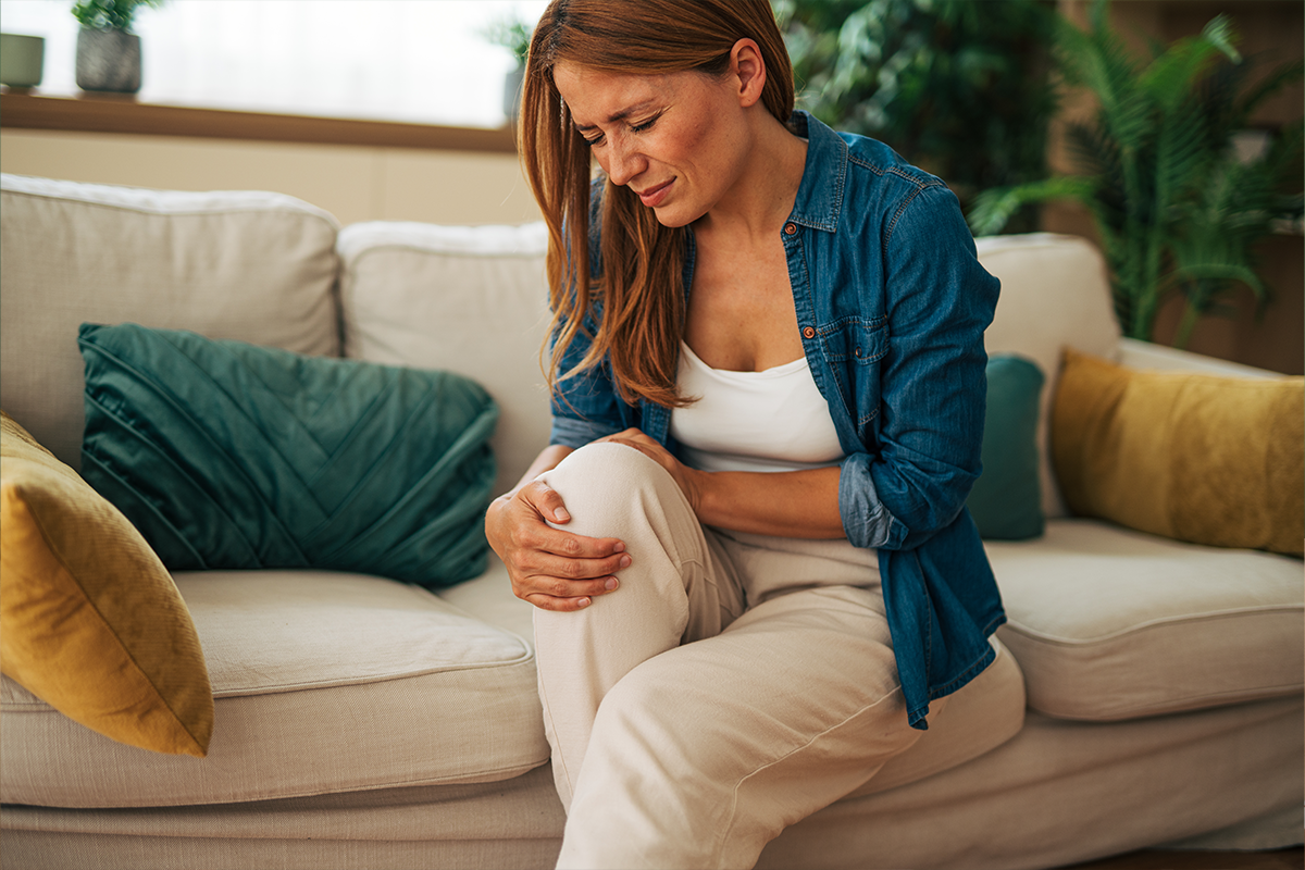 Woman sitting on couch dealing with knee pain