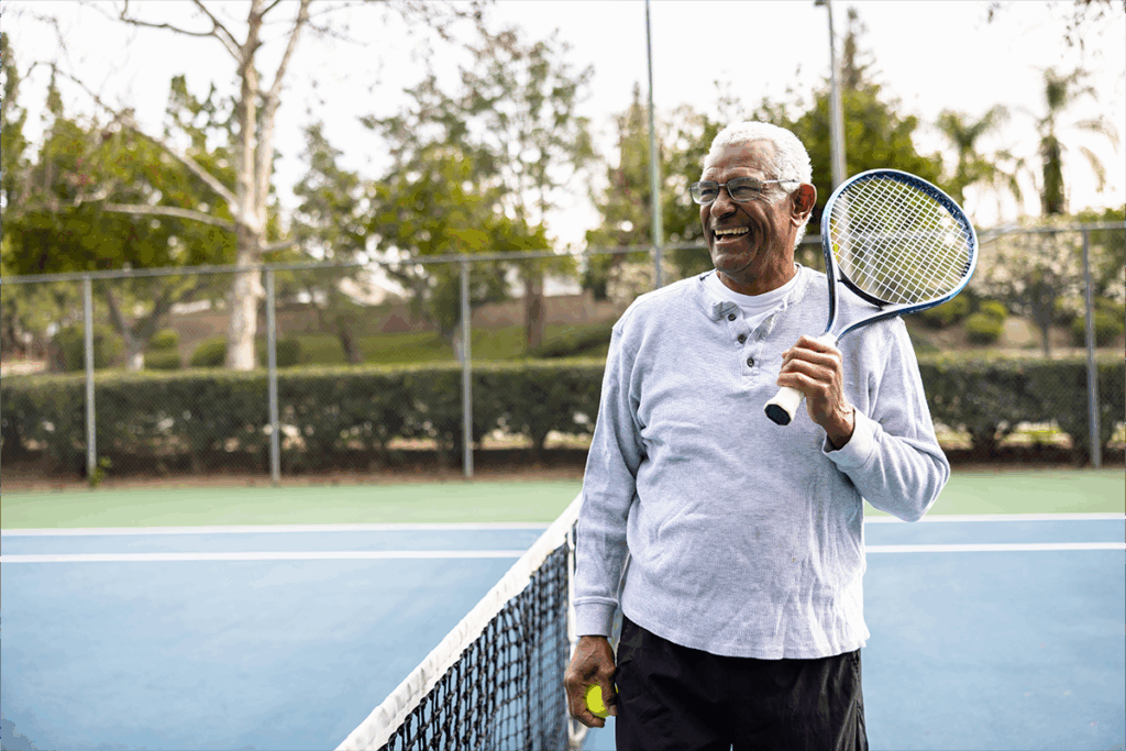 Older man on tennis court standing at the net