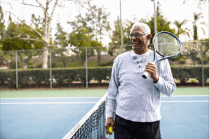 Older man on tennis court standing at the net