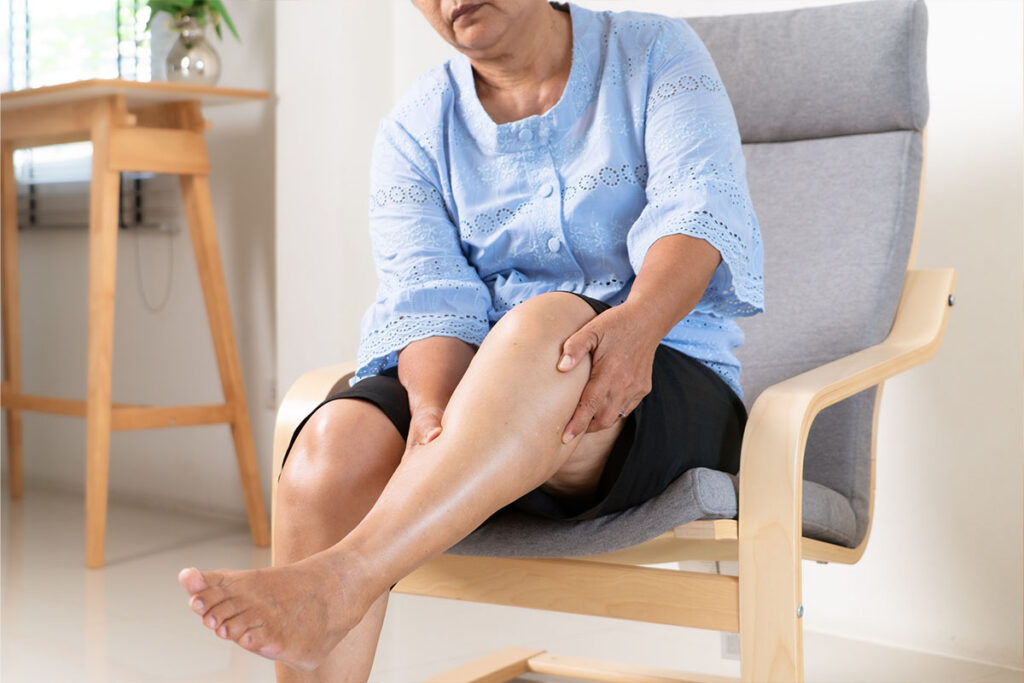 Older woman feeling behind her knee while sitting.