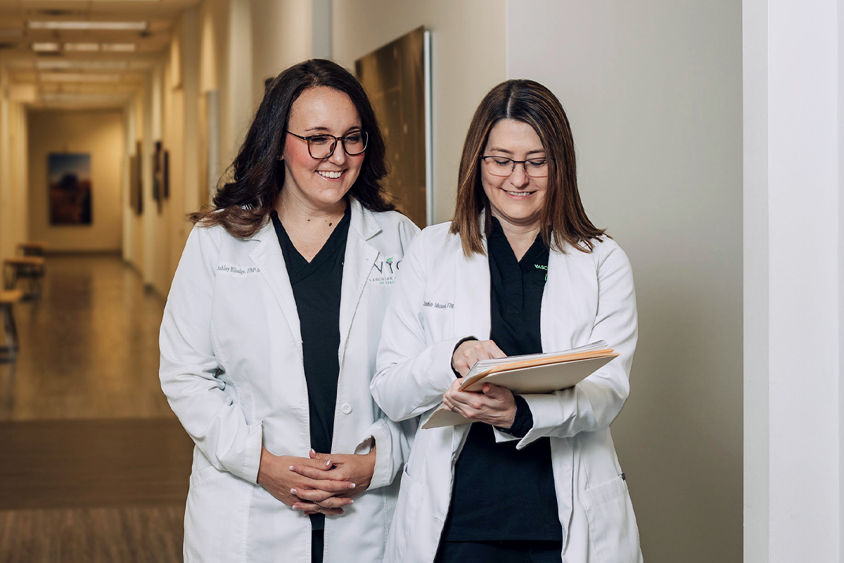 Two female physicians looking over documents in the hall