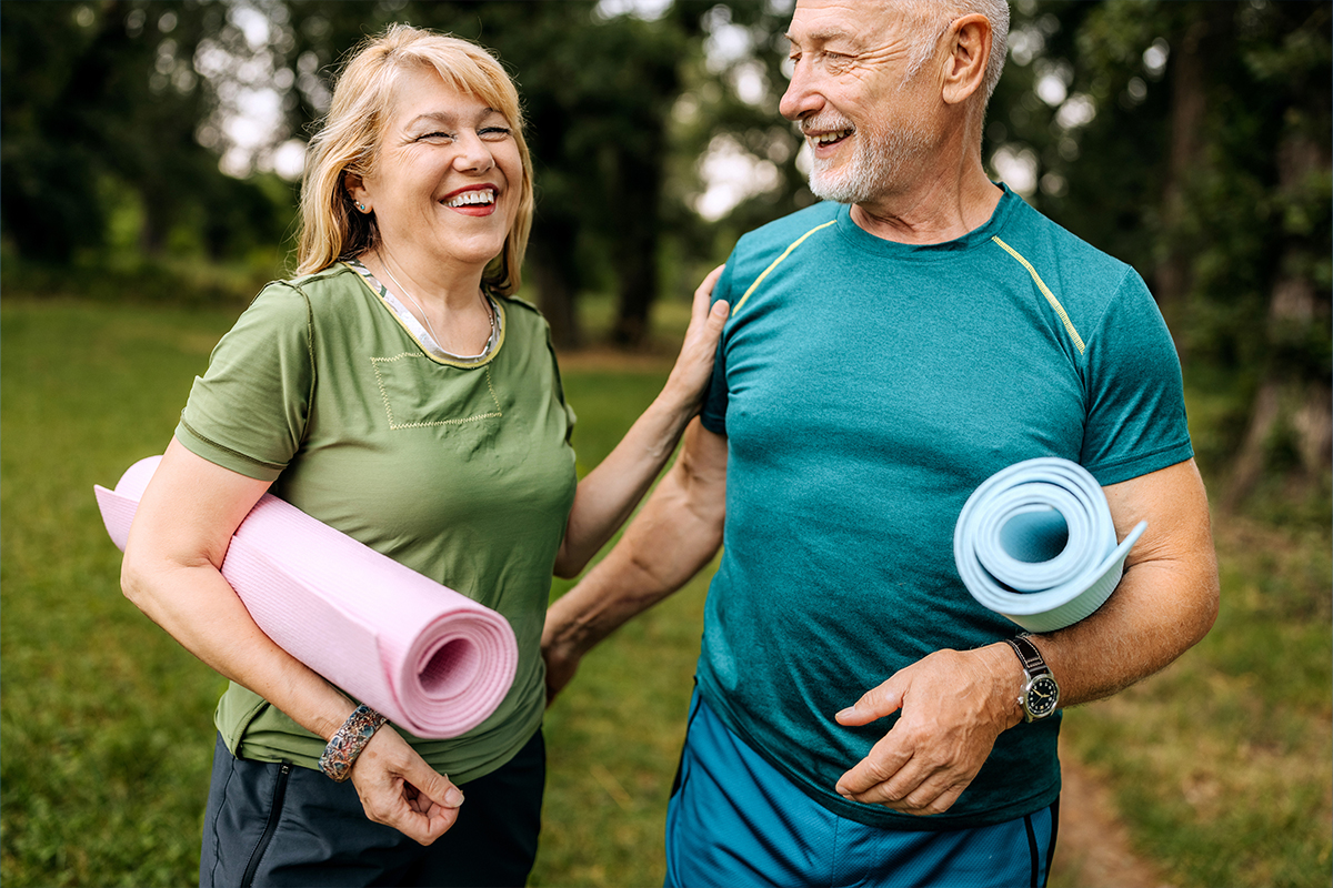 Older couple carrying yoga mats outside