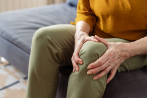 Person feeling knee joint pain while sitting