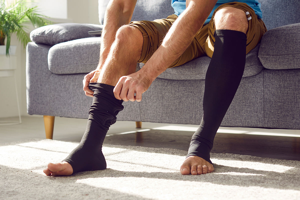 man sitting to put compression socks on legs