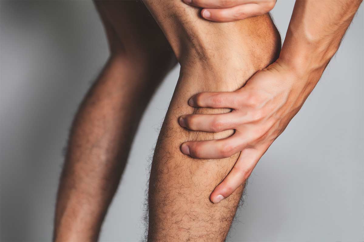 Person reaching down and feeling around their knee